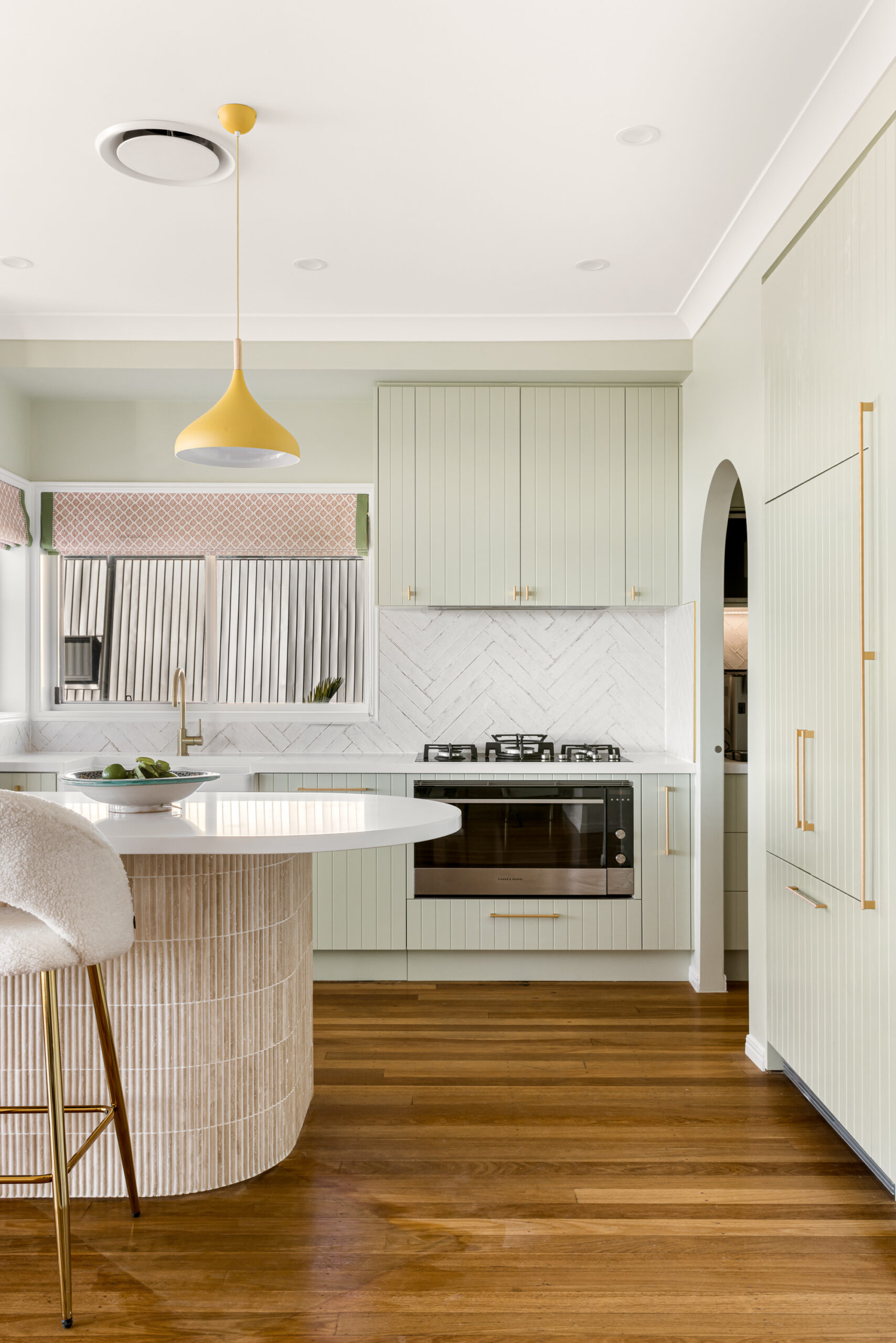 Modern kitchen with butlers kitchen, including golden handles on teal cupboards, and white accents.